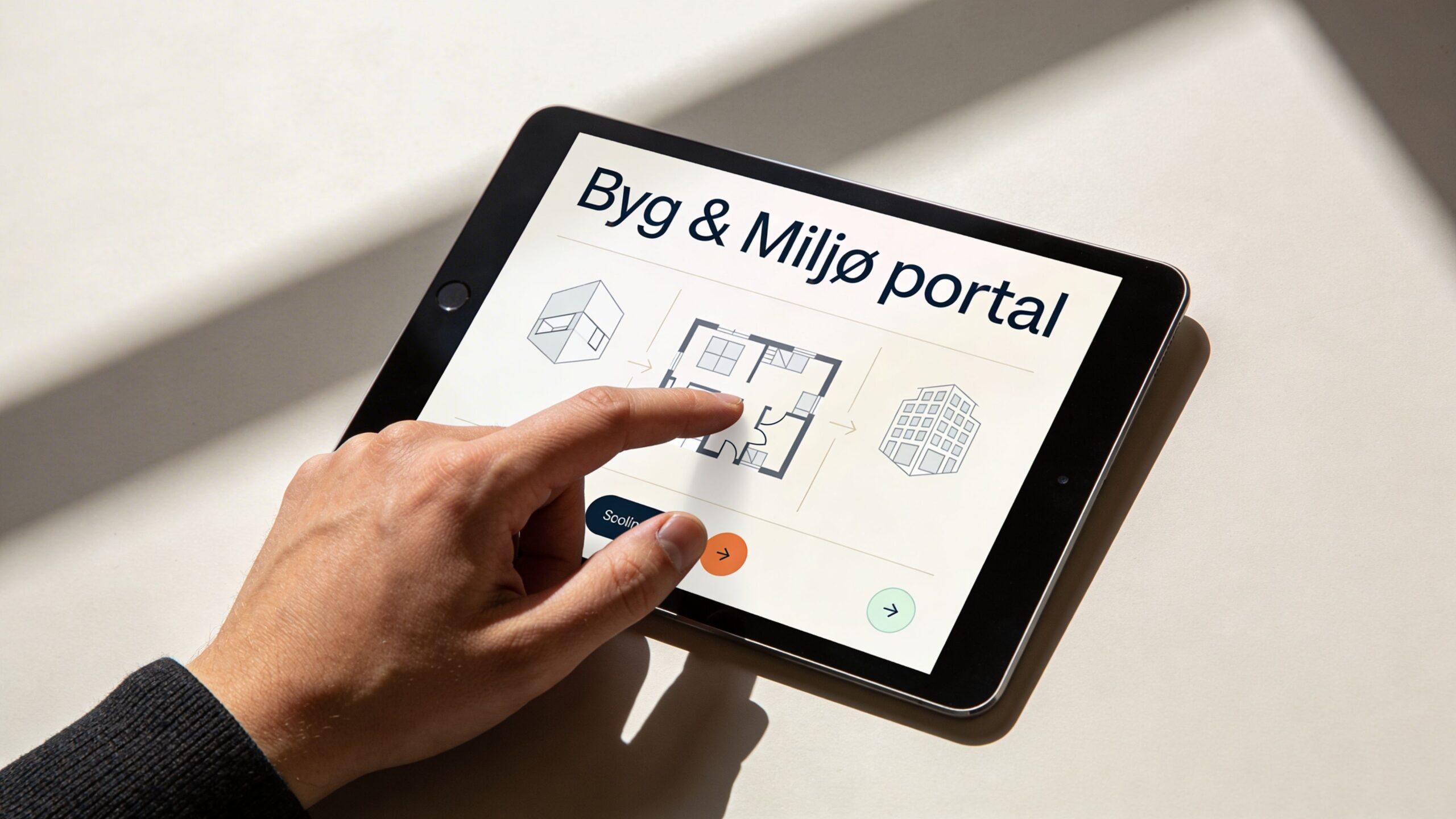 En person bruger en tablet til at navigere på Byg & Miljø portalen for at ansøge om byggetilladelse.