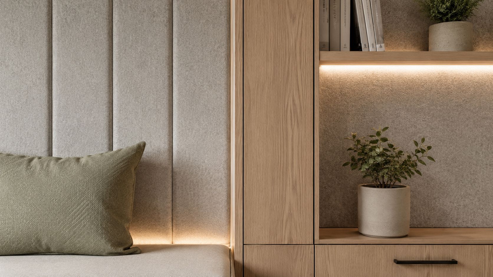 Moderne interiør med polstret beige vægpanel, træreol med bøger, grøn pude og en lille potteplante i stuen.
